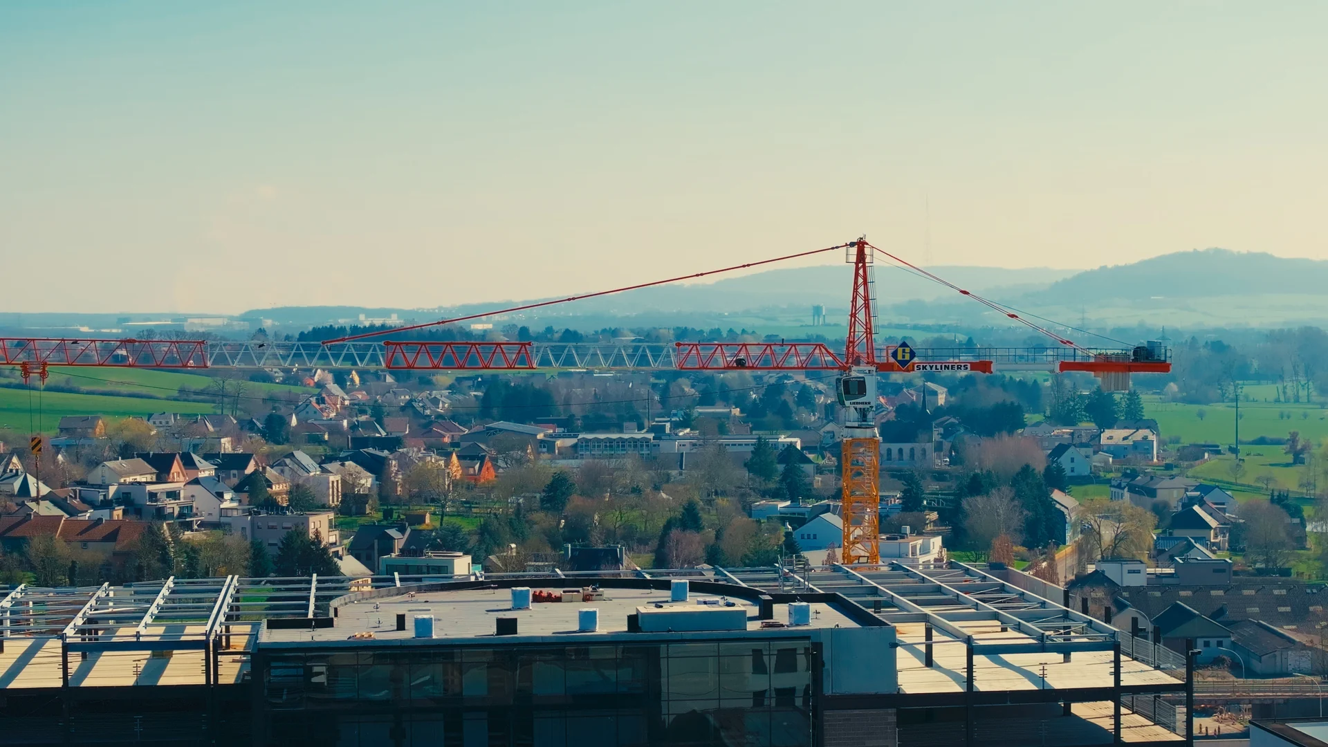 Crane above the structure and roof of GRIDX, with the surrounding landscape in the background.